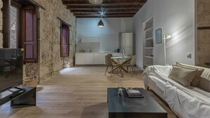 A modern living room with a wooden floor, a sofa, a coffee table, and a dining area with chairs and a table.