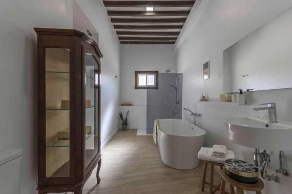 Un bagno moderno con una vasca freestanding, uno specchio grande e un mobile in legno.