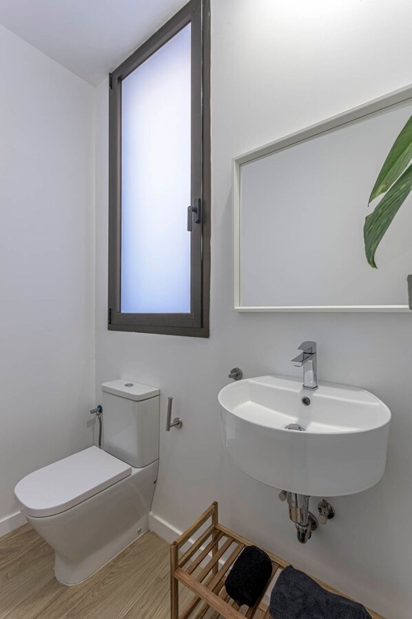 Un baño con inodoro, lavamanos y ventana.