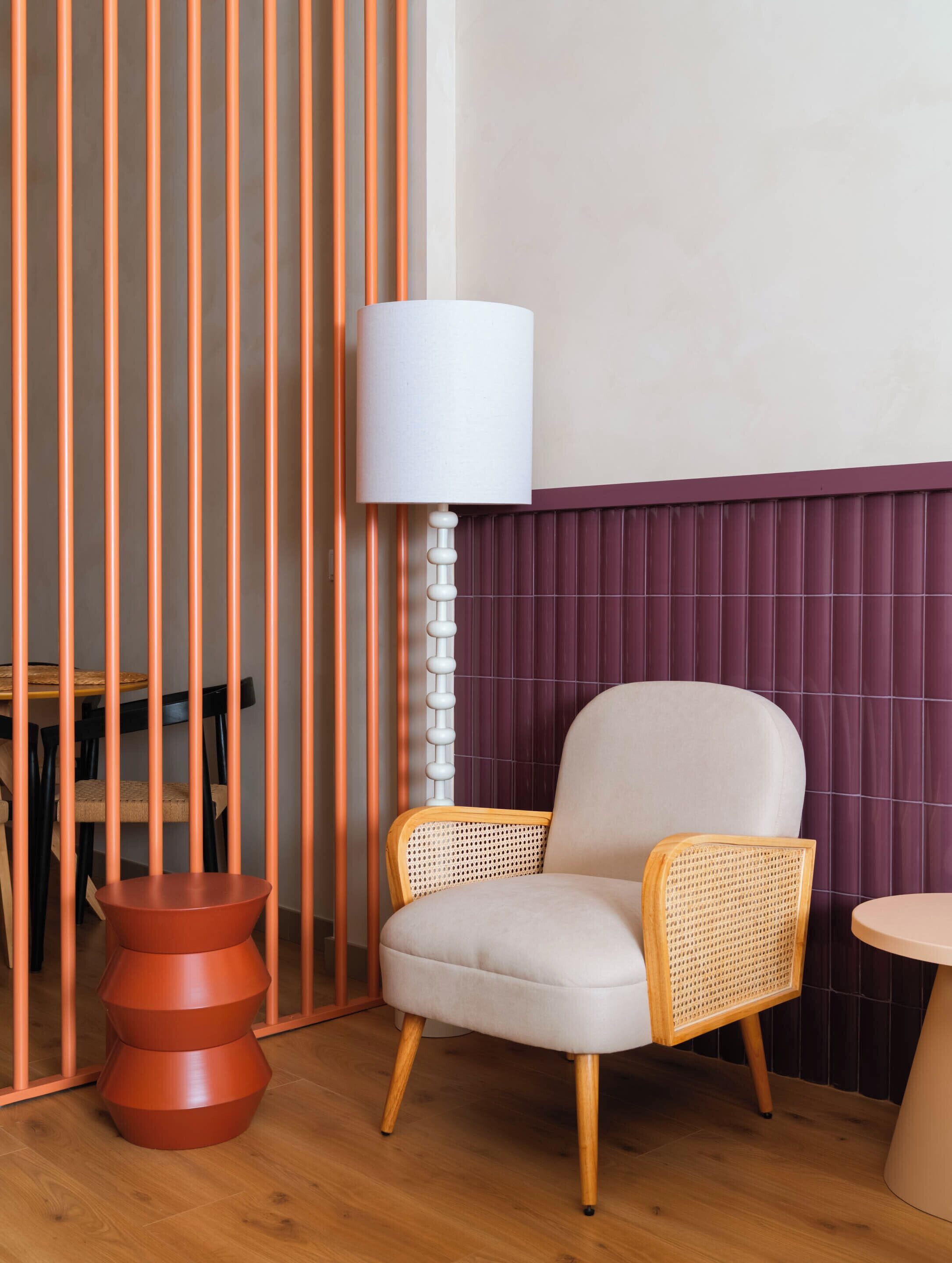 Una habitación moderna con una silla de ratán, una lámpara de pie alta y una mesa de madera.