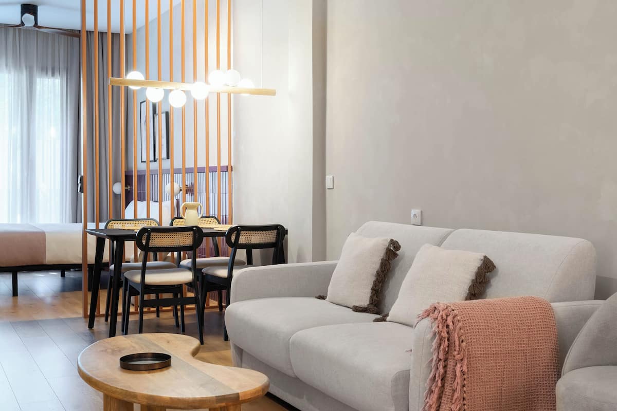 Un soggiorno moderno con un divano grigio, un tavolino rotondo in legno e un'area pranzo con tavolo e sedie.
