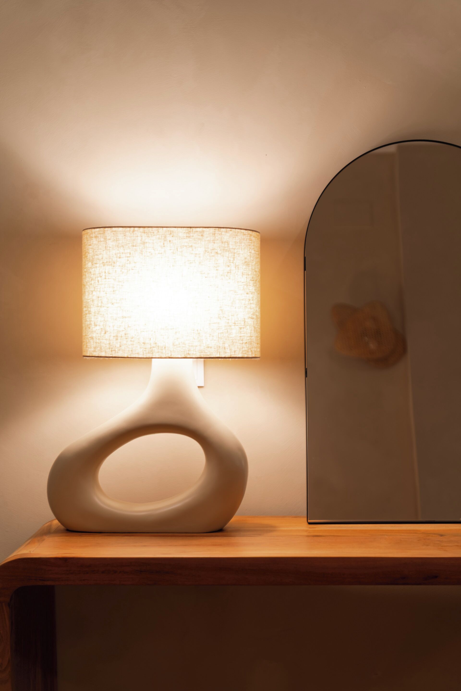 Une lampe moderne à la forme originale, posée sur une surface en bois.