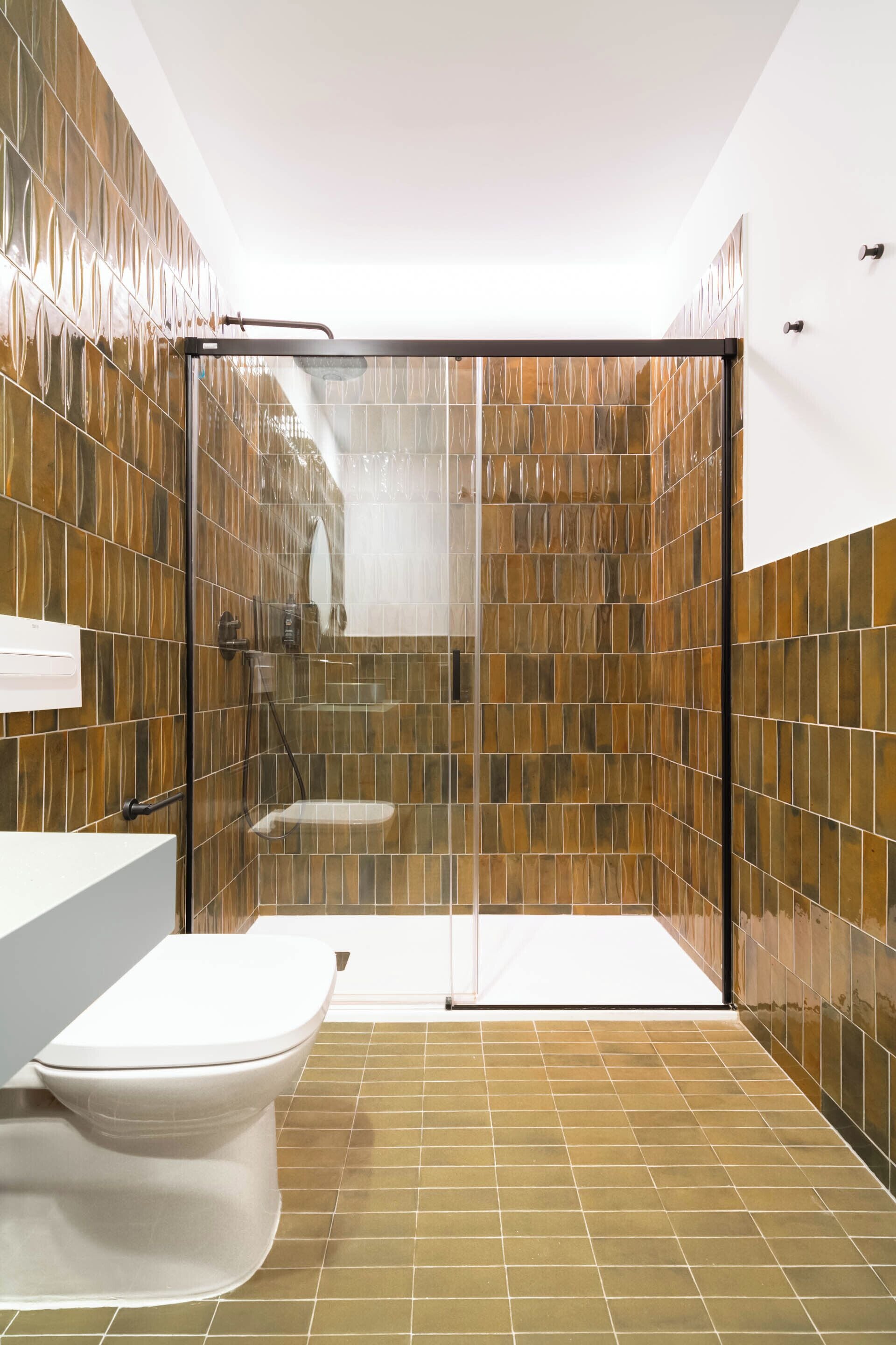 A modern bathroom with a glass-enclosed shower, a white toilet, and a tiled floor.