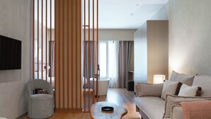 Un salon moderne comprenant un canapé, une petite table, un fauteuil et un paravent décoratif.