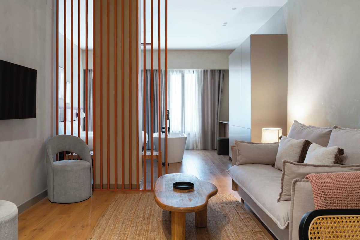 Un soggiorno moderno con un divano, un tavolino, una sedia e un paravento decorativo.