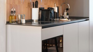 Une cuisine moderne avec un plan de travail noir, des appareils en acier inoxydable et un pare-feu en bois.