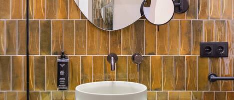Un baño con un lavabo blanco, un espejo grande y una pared con diseño de baldosas estampadas.