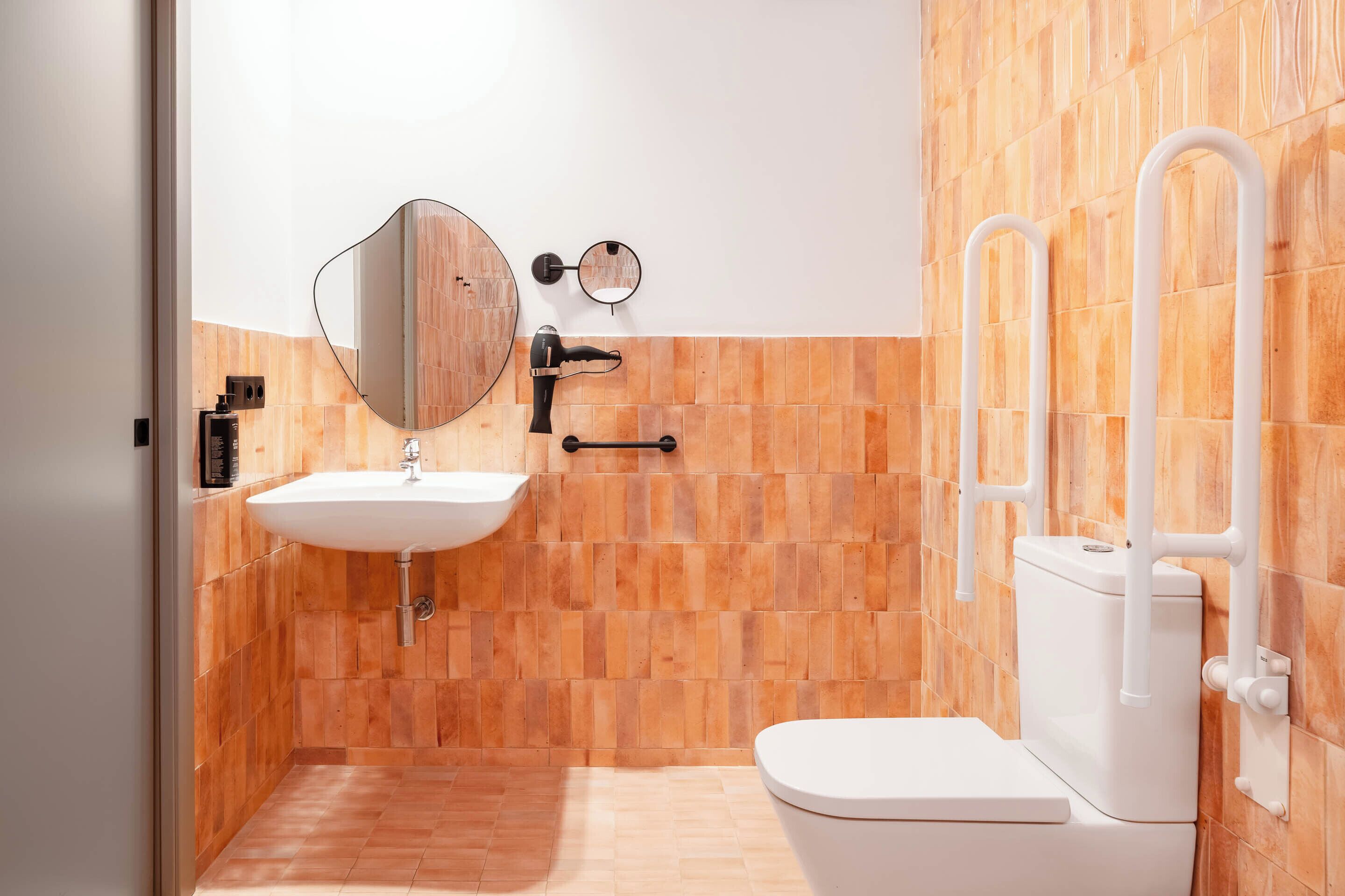 A bathroom with a wooden wall, a white sink, a mirror, and a toilet.