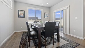 A dining room with a rectangular table, black chairs, and a patterned rug.