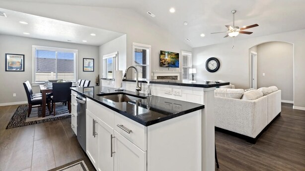 A modern kitchen with white cabinetry, a black countertop, and a dining area with a table and chairs.