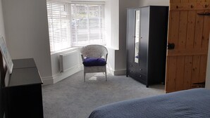 A bedroom with a bed, a chair, a wardrobe, and a radiator.