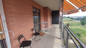 A balcony with a tiled floor, two black chairs, a drying rack, and a view of a green landscape. - Lucky House - Palace & Stadium (Venaria Reale)