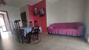 A dining area with a table and chairs, a pink sofa, and a red wall with two paintings. - Lucky House - Palace & Stadium (Venaria Reale)