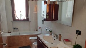 A bathroom with a bathtub, toilet, sink, and a washing machine. - Lucky House - Palace & Stadium (Venaria Reale)