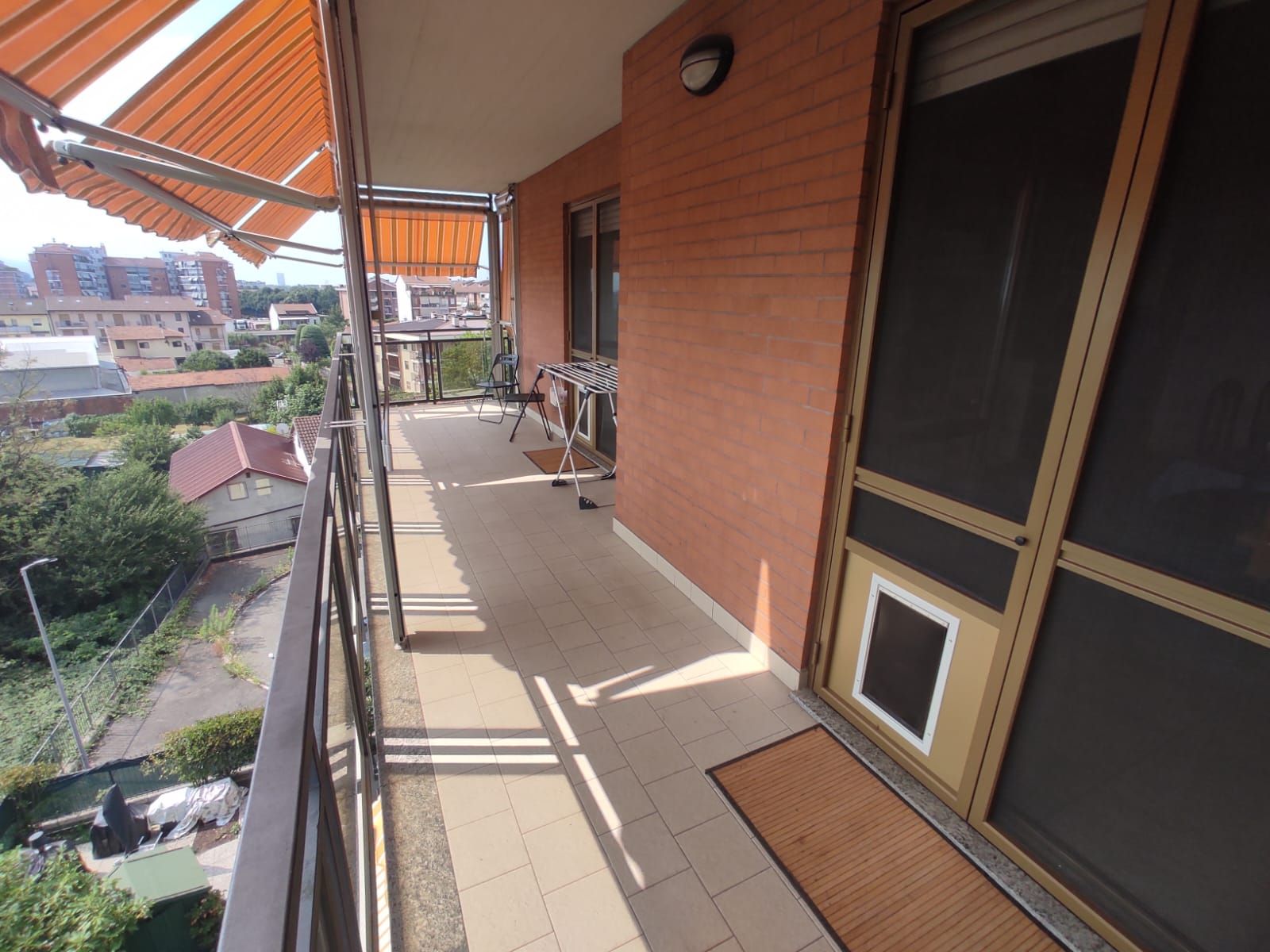 Un balcon avec une balustrade en métal, une table, des chaises et un étendoir.