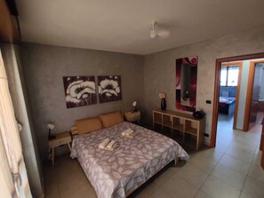 A bedroom with a bed, nightstands, a mirror, and artwork on the wall.