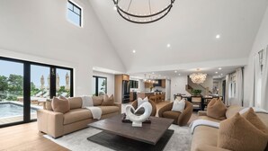 A spacious living room with a large sectional sofa, a coffee table, and a view of a swimming pool.