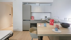 Une cuisine compacte avec un coin repas, un lit et une petite salle de bain.