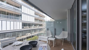 Un espace repas moderne avec une table dressée pour deux personnes, deux chaises blanches et une table en verre.