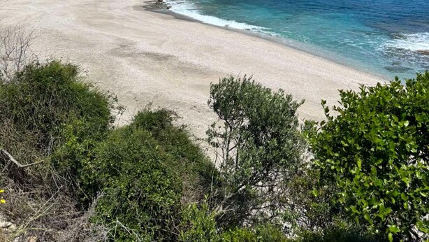 A beach with clear blue water, sandy shore, and green hills in the background. - Villa Apanemia Tsakaioi (Karystos)