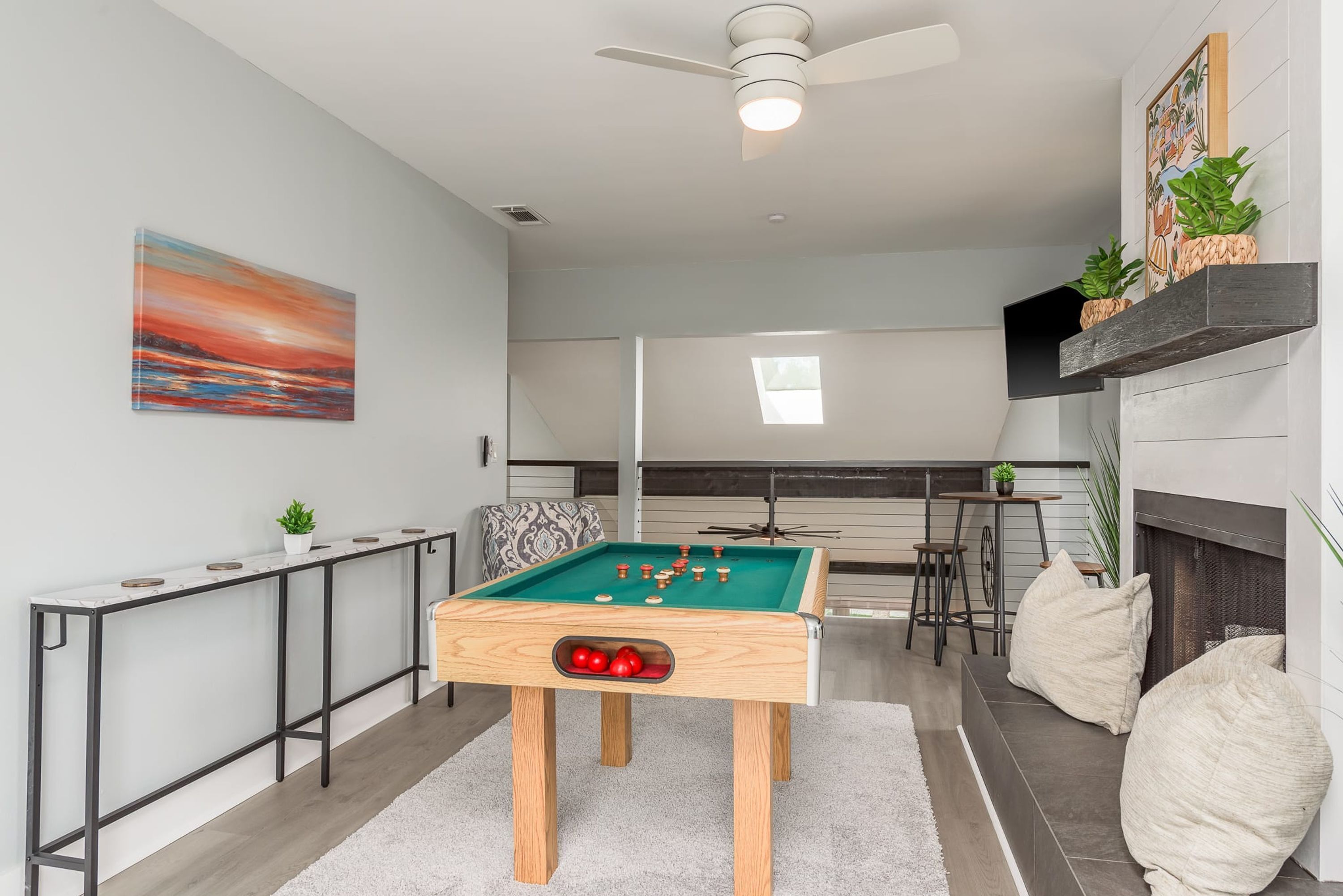 A pool table in a modern living room with a ceiling fan, a fireplace, and a view of the living area.