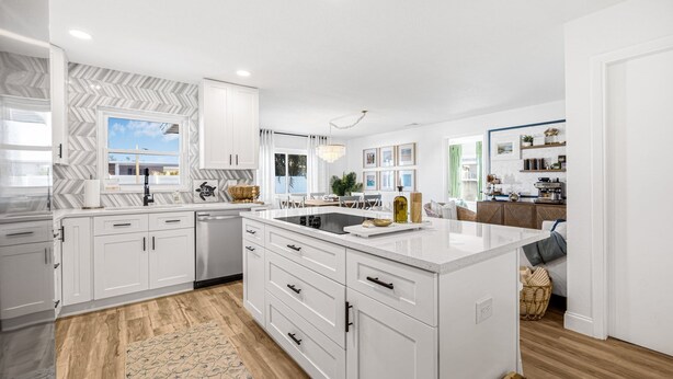 A modern kitchen with white cabinetry, a large island, and a herringbone-patterned backsplash. - Castaway Cottage Near IMG and Beaches (Bradenton)