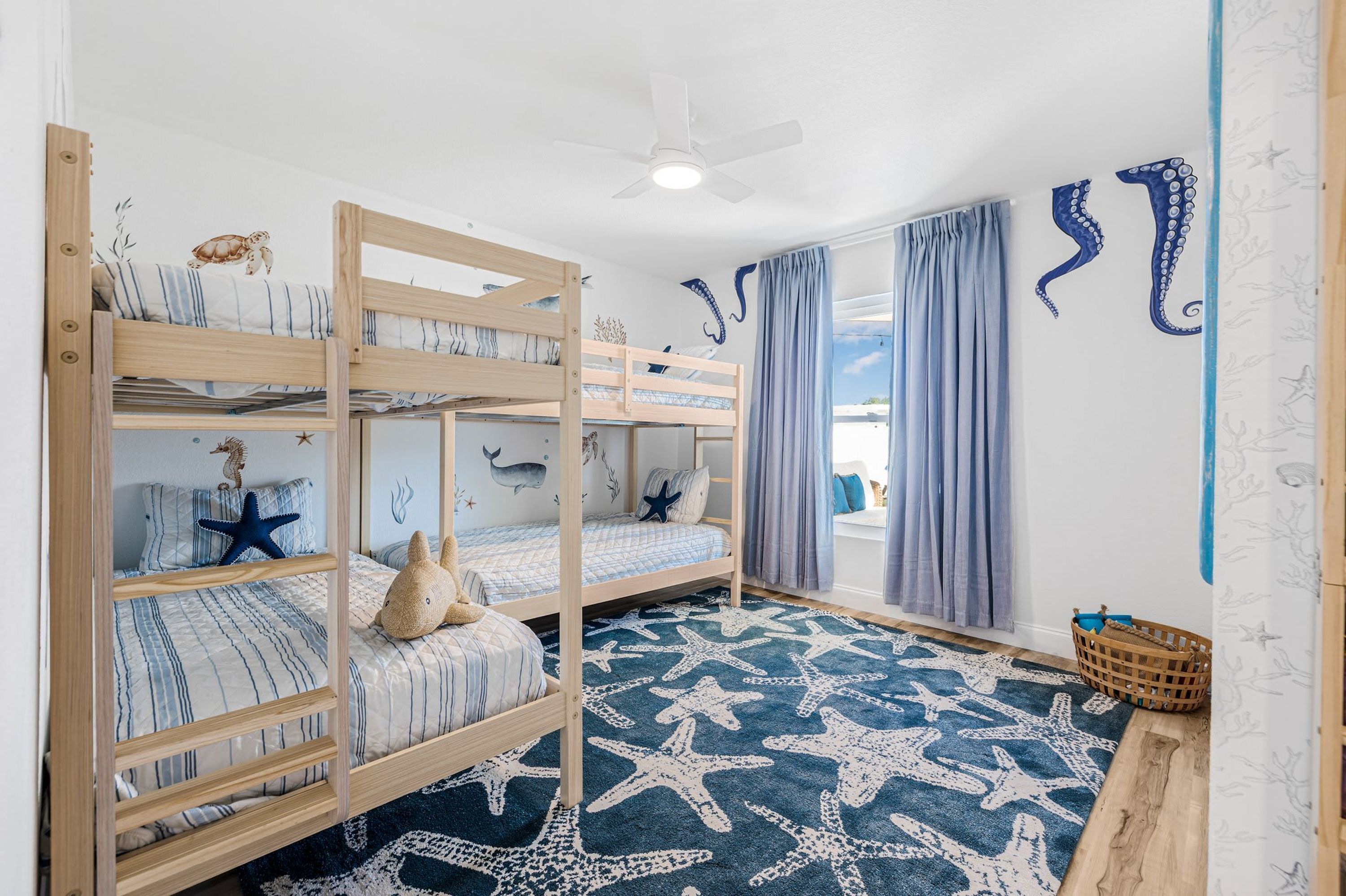 A child’s bedroom with bunk beds, starfish-themed decor, and a starfish-patterned rug.