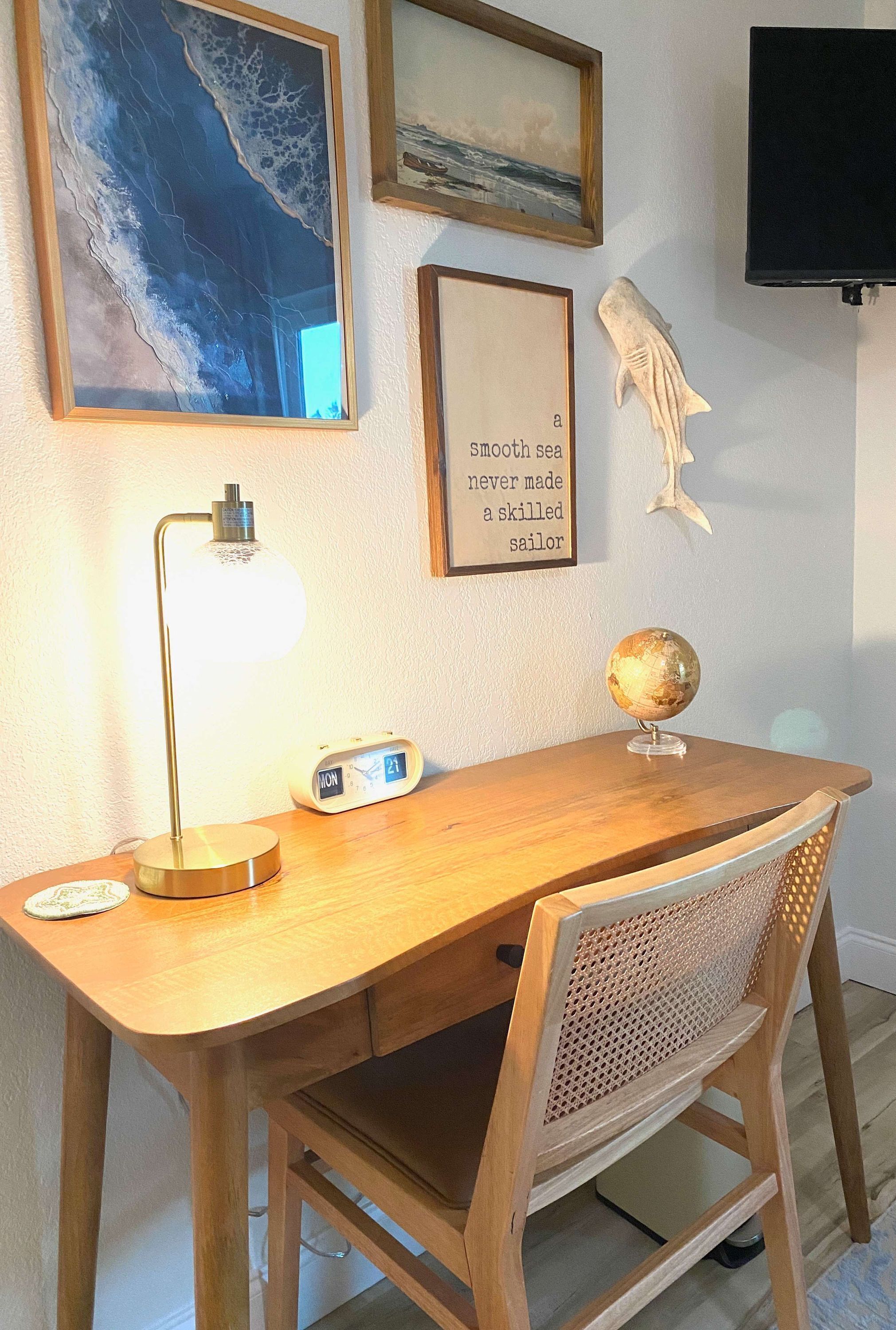 Un escritorio de madera con un globo terráqueo, una cita enmarcada y una escultura de pez en la pared.