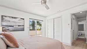 A bedroom with a bed, a ceiling fan, a large window, and a door leading to a balcony. - Stylish Villa Near Treasure Island Beaches (Treasure Island)