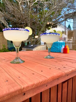Zwei Margaritas auf einem Holztisch im Freien.