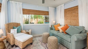 Ein Zimmer mit einem Korbstuhl, einem grünen Sofa und einem Deckenventilator.