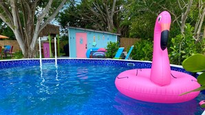 A swimming pool with a pink flamingo float.