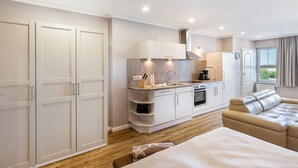 Une cuisine moderne dotée d’un four encastré, un coin repas avec un canapé et une grande armoire.