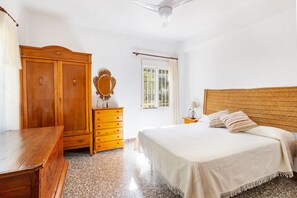 Un dormitorio con cama, armario de madera, cómoda y ventana con cortinas.