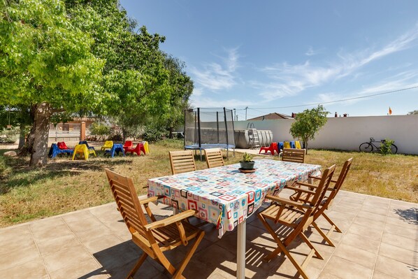 Une terrasse avec une table et des chaises, un arbre et une clôture.