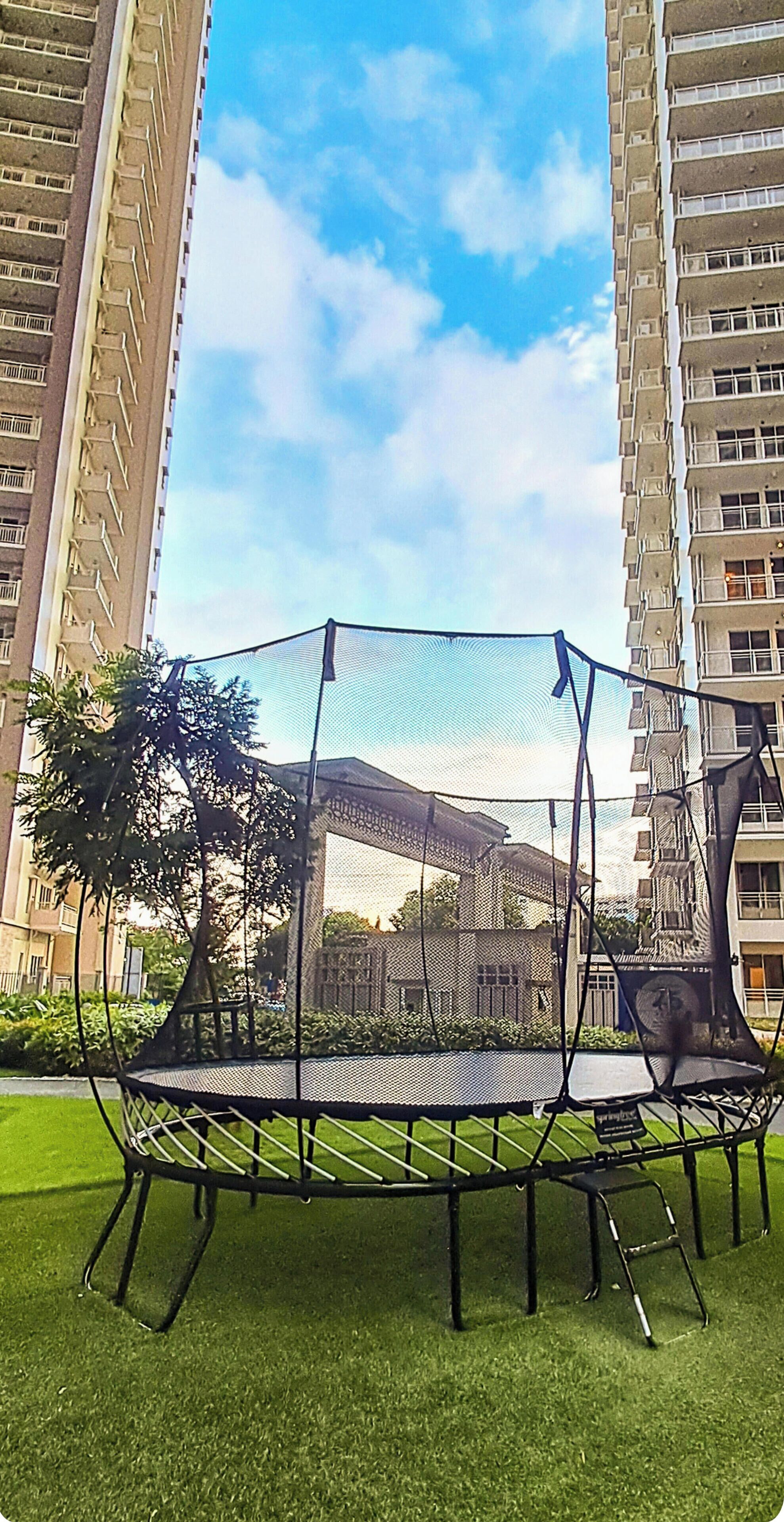 Un trampolino su un'area erbosa, sullo sfondo edifici alti.