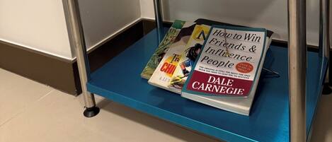 A small table with a white PLDT Home WiFi router, a potted plant, and a book titled "How to Win Friends & Influence People" by Dale Carnegie.