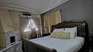 Ein Schlafzimmer mit einem großen Bett, einem Kamin und einer Deckenleuchte.