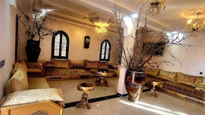 Ein großzügiger Lounge-Bereich mit hoher Decke, aufwendigen Kronleuchtern und einer zentralen Sitzecke.
