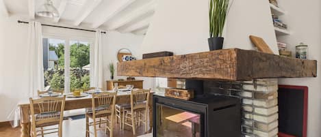 A cozy living room with a stone fireplace, wooden dining table, and chairs.