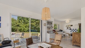 Amplia sala de estar con una mesa de comedor, sillas, una cocina y un ventanal corredizo que da a un jardín.