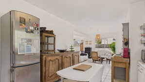 Una cocina moderna con un refrigerador de acero inoxidable, muebles de madera, una mesa de comedor y vistas al exterior.