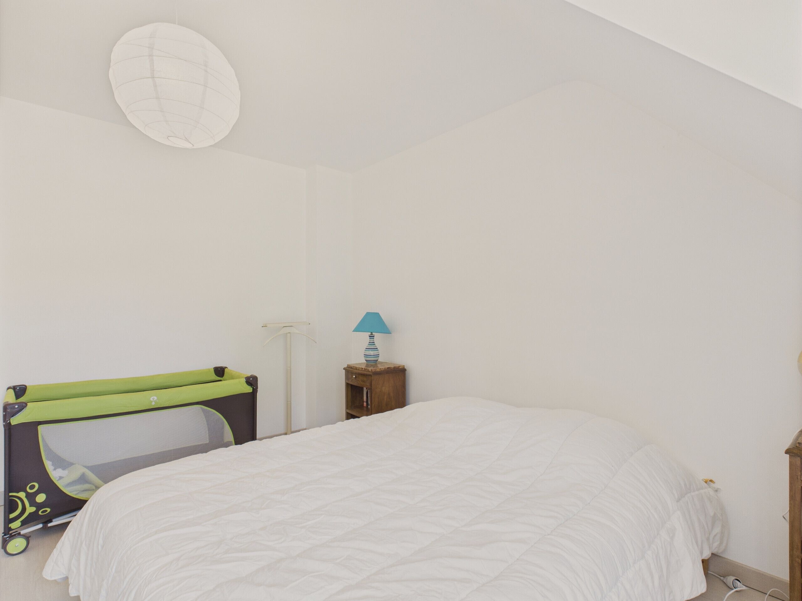 Un dormitorio con cama, cuna, lámpara y luz empotrada en la pared.