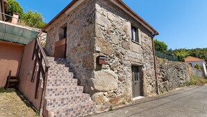 Un edificio de piedra con una pequeña escalera que lleva a una puerta, una ventana y un buzón.
