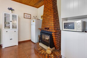 Eine Küche mit Kamin aus Ziegeln, weißen Schränken und einer Mikrowelle.