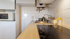 Una cocina con microondas, pileta y grifo de acero inoxidable.