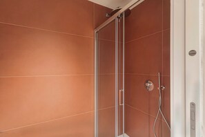 Studio | Badkamer | Een douche, een haardroger, handdoeken, zeep