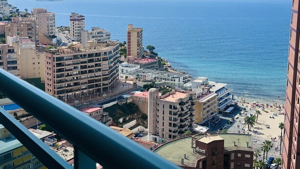 A coastal cityscape with a beach, high-rise buildings, and a clear view of the sea.
