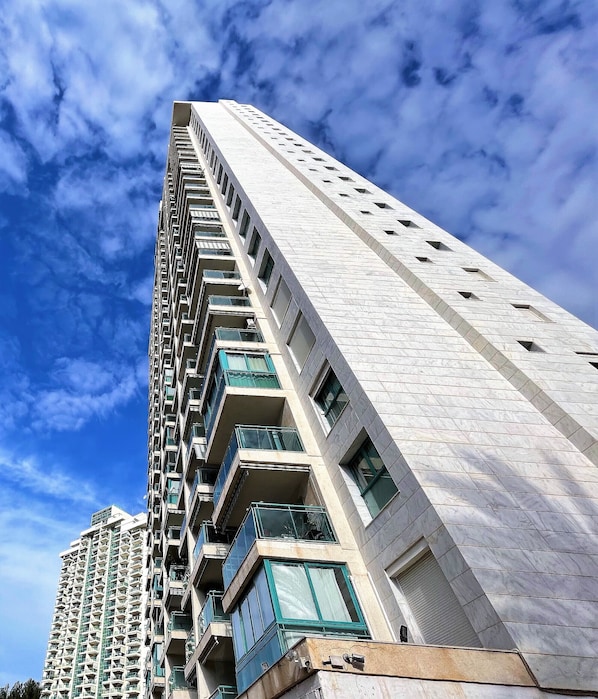 A high-rise building with multiple balconies and a clear sky.