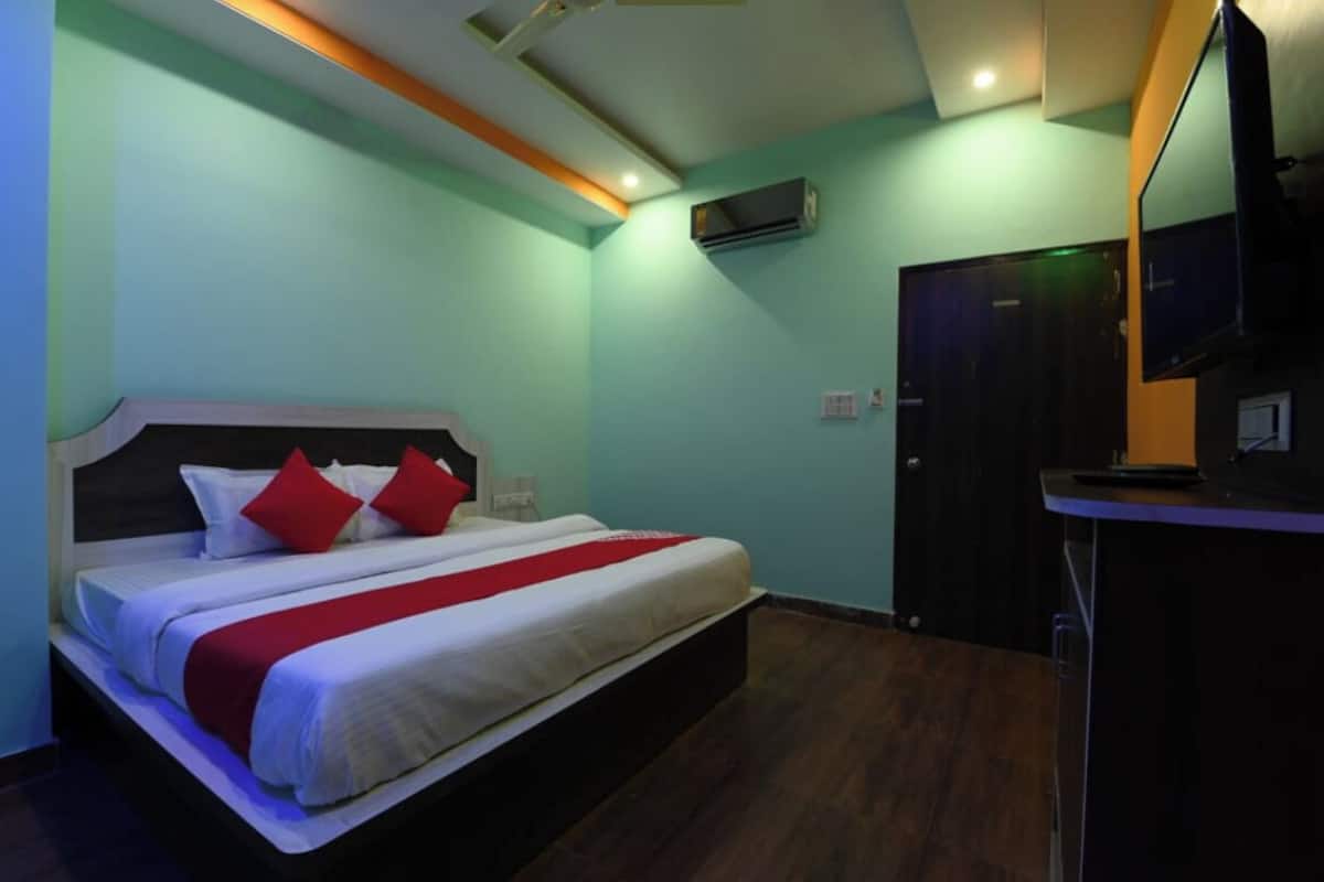 Una habitación de hotel con cama, escritorio, aire acondicionado y puerta.